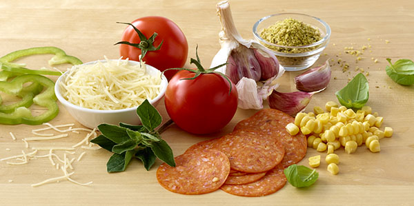 Frische Zutaten: Tomaten, Käse, Peperoni, Paprika, Knoblauch, Basilikum und Mais