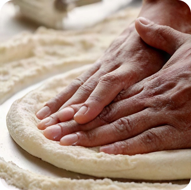 Frischer Pizzateig wird von Hand ausgerollt